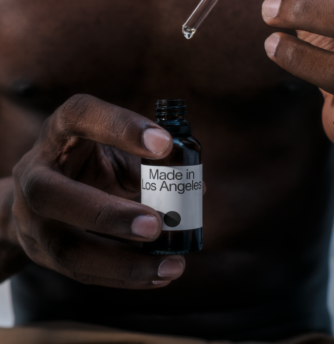 Person holding a labeled dropper bottle with pipette for cosmetic mockup graphic design.